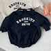 Baby romper with college-style New York print – soft cotton, popper fastening | unisex 0–2 years